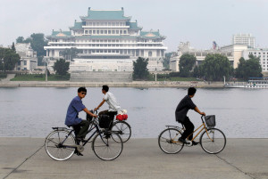 bicyclists peddling alongside the Taedong River across from the Juche Tower in Pyongyang, North Korea